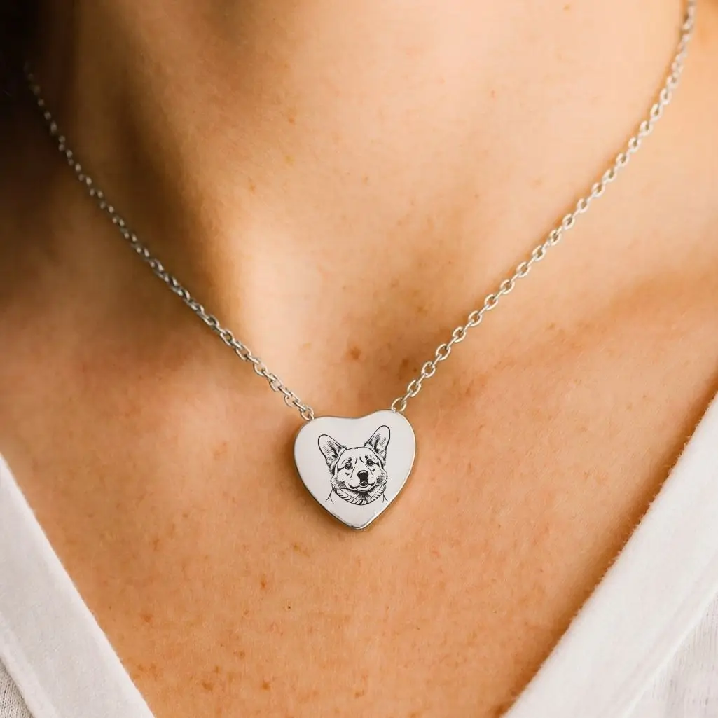 Silver heart-shaped necklace engraved with a dog’s face, worn close to the neck as a memorial keepsake for a beloved pet.